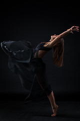 Image showing Young beautiful dancer in beige dress dancing on black background