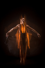 Image showing Young beautiful dancer in beige dress dancing on black background