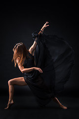 Image showing Young beautiful dancer in beige dress dancing on black background