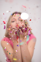 Image showing woman blowing confetti in the air