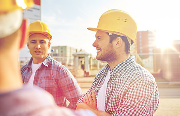 Image showing group of smiling builders in hardhats outdoors