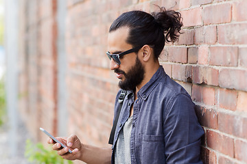 Image showing man with backpack texting on smartphone in city