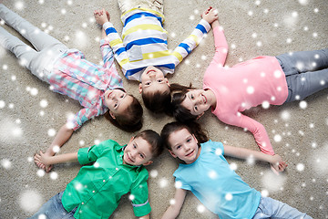 Image showing happy smiling children lying on floor over snow