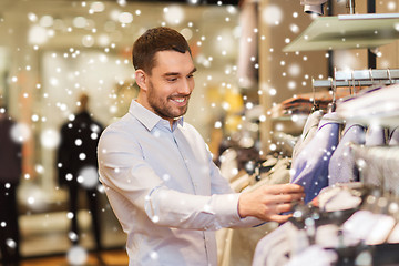 Image showing happy young man choosing clothes in clothing store