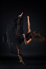 Image showing Young beautiful dancer in beige dress dancing on black background