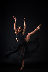 Image showing Young beautiful dancer in beige dress dancing on black background