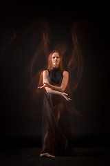 Image showing Young beautiful dancer in beige dress dancing on black background