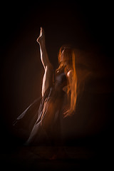 Image showing Young beautiful dancer in beige dress dancing on black background