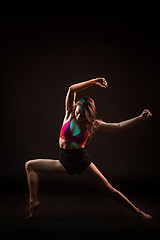 Image showing Young beautiful dancer in beige dress dancing on black background