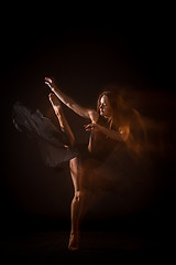 Image showing Young beautiful dancer in beige dress dancing on black background