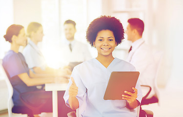 Image showing happy doctor with tablet pc over team at clinic