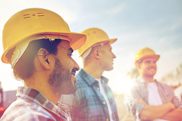 Image showing group of smiling builders in hardhats outdoors