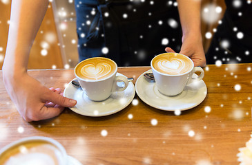 Image showing close up of hands with latte art in coffee cup