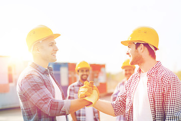 Image showing group of smiling builders in hardhats outdoors