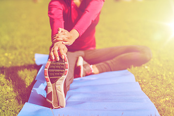 Image showing close up of woman stretching leg on mat outdoors