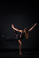 Image showing Young beautiful dancer in beige dress dancing on black background