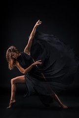 Image showing Young beautiful dancer in beige dress dancing on black background