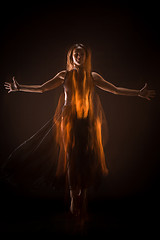 Image showing Young beautiful dancer in beige dress dancing on black background