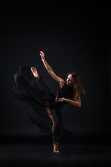 Image showing Young beautiful dancer in beige dress dancing on black background