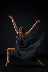 Image showing Young beautiful dancer in beige dress dancing on black background