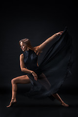 Image showing Young beautiful dancer in beige dress dancing on black background