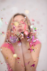 Image showing woman blowing confetti in the air