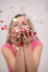 Image showing woman blowing confetti in the air