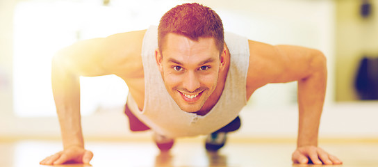 Image showing smiling man doing push-ups in the gym