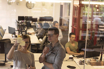 Image showing young couple at modern office interior writing notes on stickers