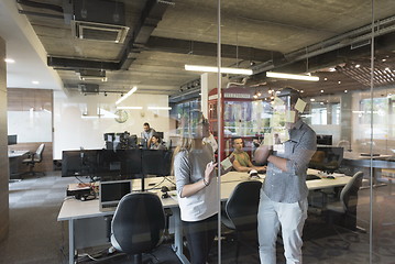 Image showing young couple at modern office interior writing notes on stickers