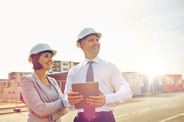 Image showing happy builders in hardhats with tablet pc outdoors