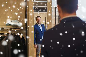 Image showing man trying jacket on at mirror in clothing store