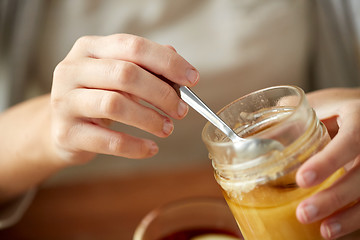 Image showing close up of woman hands with honey jar and spoon