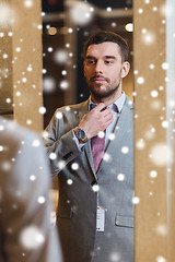 Image showing man trying jacket on at mirror in clothing store