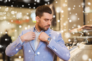 Image showing young man trying jacket on in clothing store