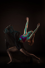 Image showing Young beautiful dancer in beige dress dancing on black background