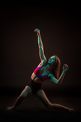 Image showing Young beautiful dancer in beige dress dancing on black background