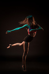 Image showing Young beautiful dancer in beige dress dancing on black background