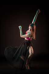 Image showing Young beautiful dancer in beige dress dancing on black background
