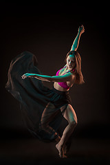 Image showing Young beautiful dancer in beige dress dancing on black background