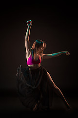 Image showing Young beautiful dancer in beige dress dancing on black background