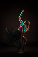 Image showing Young beautiful dancer in beige dress dancing on black background