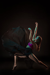 Image showing Young beautiful dancer in beige dress dancing on black background