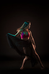 Image showing Young beautiful dancer in beige dress dancing on black background