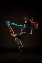 Image showing Young beautiful dancer in beige dress dancing on black background