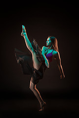 Image showing Young beautiful dancer in beige dress dancing on black background