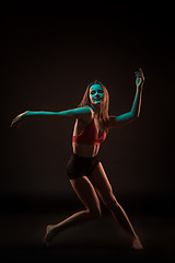 Image showing Young beautiful dancer in beige dress dancing on black background