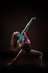 Image showing Young beautiful dancer in beige dress dancing on black background