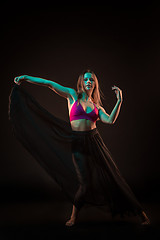 Image showing Young beautiful dancer in beige dress dancing on black background