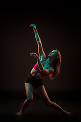 Image showing Young beautiful dancer in beige dress dancing on black background